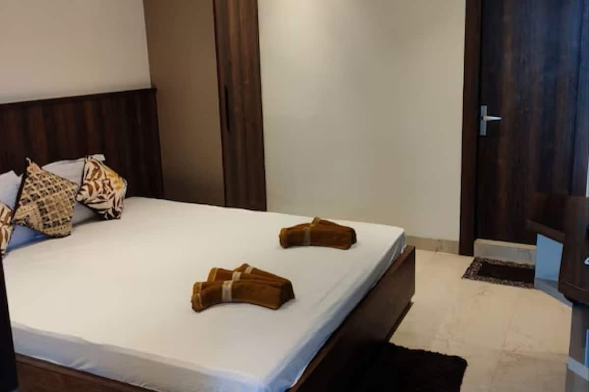 Quarto de hotel com cama, guarda-roupa, porta e tapete pequeno.