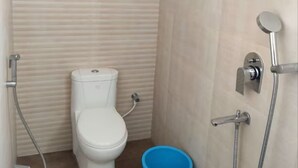 Un baño pequeño con inodoro, ducha y un cubo azul.