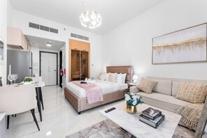 Een moderne hotelkamer met een bed, een bank, een eethoek en een schilderij aan de muur.