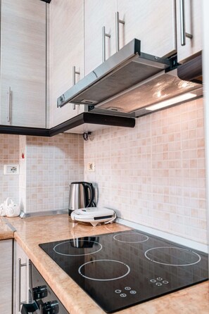 Een moderne keuken met een zwart inductiekookplaatje, een roestvrijstalen waterkoker en een inbouwoven.