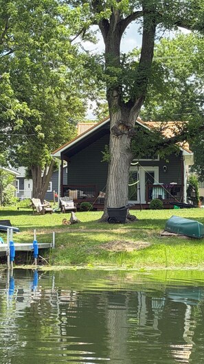 Ein Haus mit einem großen Baum davor, einem Steg und einem Rasen.