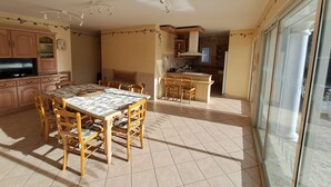 Una cocina amplia con comedor, armarios de madera, un televisor y un ventanal grande.