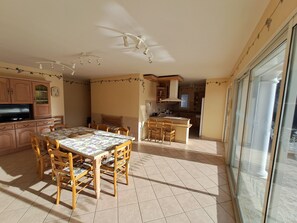 A spacious kitchen with a dining area, wooden cabinets, a TV, and a large window. - 3-bedroom house with pool, 5 minutes walk from the beach (Bandol)