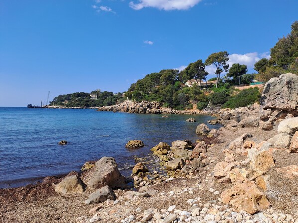A rocky shoreline with clear blue water, a distant ship, and buildings on a hillside. - 3-bedroom house with pool, 5 minutes walk from the beach (Bandol)