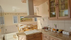 Una cocina con armarios de madera, una isla central y una zona de comedor con sillas.