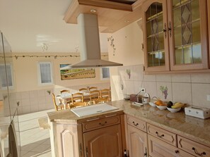 A kitchen with wooden cabinets, a central island, and a dining area with chairs. - 3-bedroom house with pool, 5 minutes walk from the beach (Bandol)