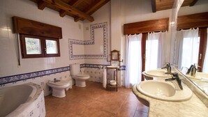 Une salle de bain avec une baignoire, deux toilettes, un lavabo et un miroir.