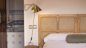 Une chambre à coucher avec une tête de lit en bois, une table de chevet, une lampe et un lit recouvert de linge de lit blanc.