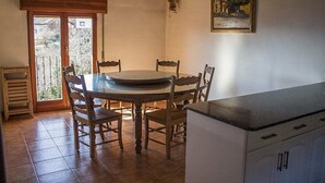 Un coin repas avec une table ronde et des chaises, une porte-fenêtre coulissante donnant sur l’extérieur et un espace cuisine avec des placards.