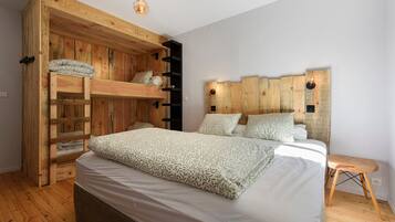 A bedroom with a bunk bed, a bedside table, and a wooden headboard.