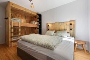 A bedroom with a bunk bed, a bedside table, and a wooden headboard.