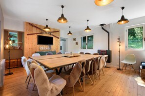 A modern dining area with a wooden table, plush chairs, and pendant lighting.