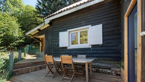 Une terrasse en bois avec une table et des chaises, une fenêtre avec des volets et une porte.