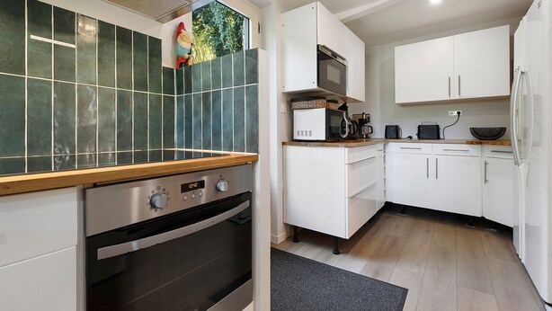 Une cuisine moderne avec des meubles blancs, un four encastré et un four à micro-ondes.