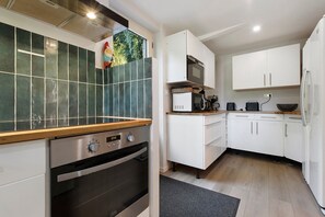 A modern kitchen with white cabinets, a built-in oven, and a microwave.