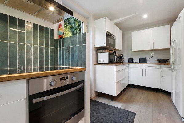 A modern kitchen with white cabinets, a built-in oven, and a microwave.