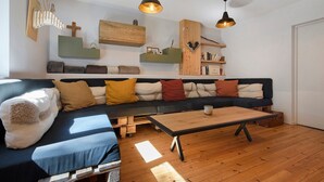 Un salon moderne avec un canapé d’angle, un plancher en bois et des luminaires suspendus.