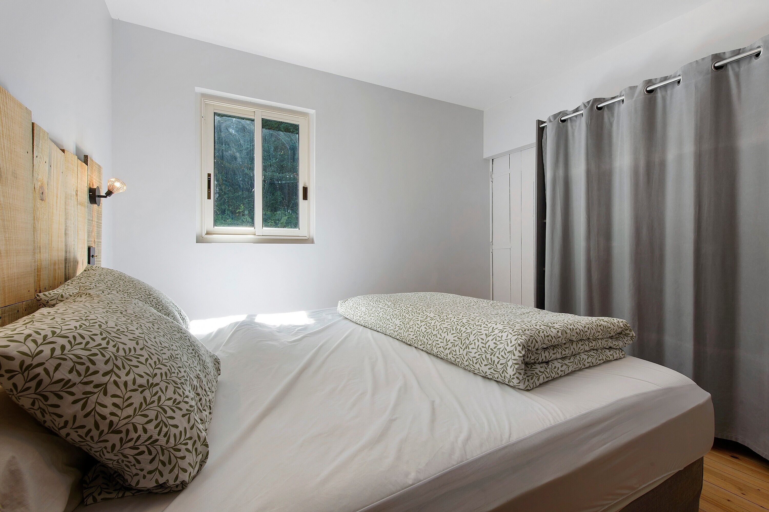 Ein Schlafzimmer mit einem Bett, einem Fenster und einem Vorhang.