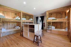 A room with bunk beds, a small table, and a stool.