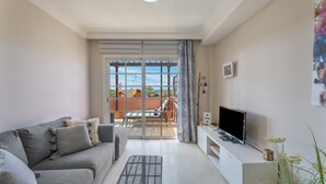 Una sala de estar con sofá, televisión y balcón con vistas.