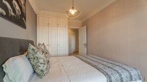 Un dormitorio con una cama, una lámpara colgante, una puerta y un pasillo.