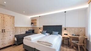 Een slaapkamer met twee bedden, een bureau en een kledingkast.