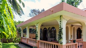 Una casa con porche cubierto, ventanas arqueadas y plantas en macetas.