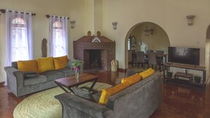 Una sala de estar con sofá, mesa de centro, chimenea, televisor y comedor.