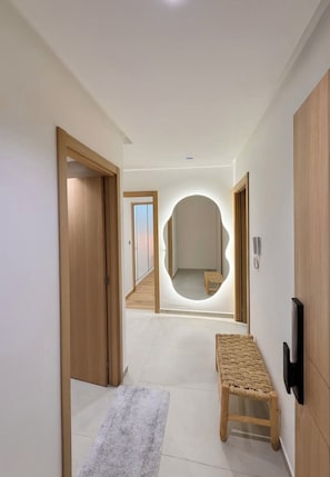 A modern hallway with a wooden bench, a circular mirror, and a flat-screen TV mounted on the wall. - Luxury Apartment• Wintering-Piscine-Centre Guéliz (Marrakech)