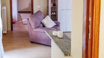 A living room with a purple sofa, a white cabinet, and a small table with two white candles.