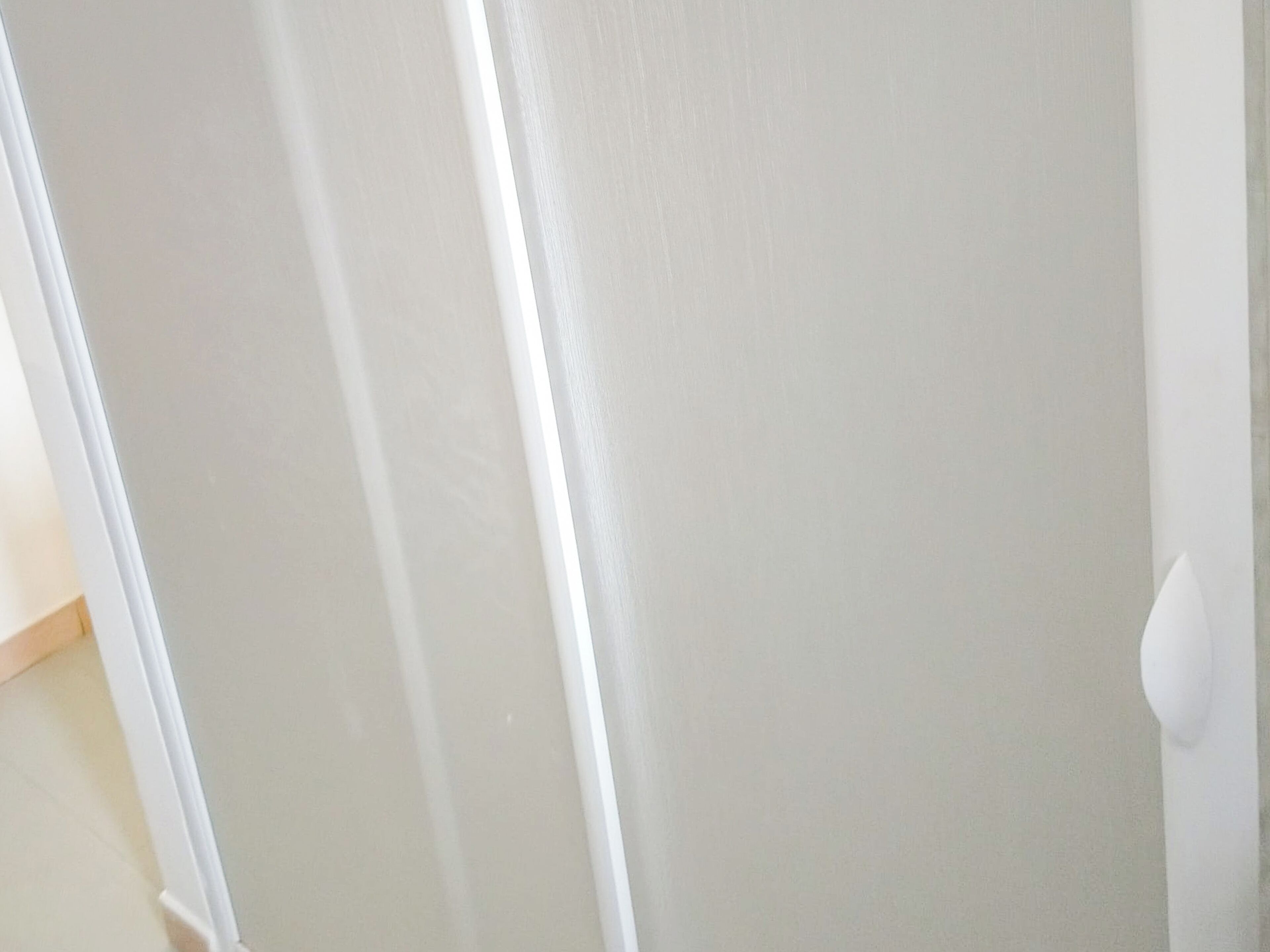Una puerta blanca con manija, una pared blanca y un suelo de madera.