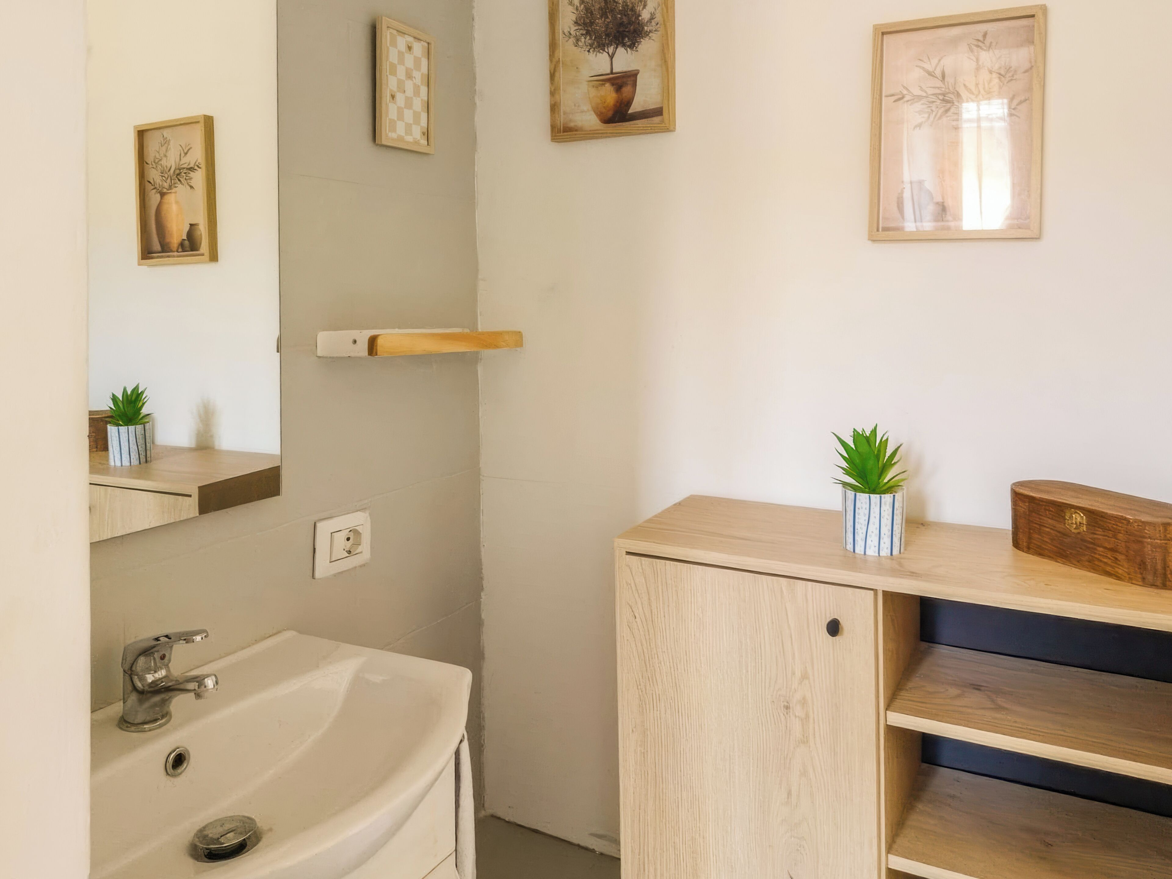 Ein Badezimmer mit Waschbecken, Spiegel und einem gerahmten Kunstwerk an der Wand.
