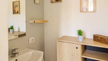 Ein Badezimmer mit Waschbecken, Spiegel und einem gerahmten Kunstwerk an der Wand.