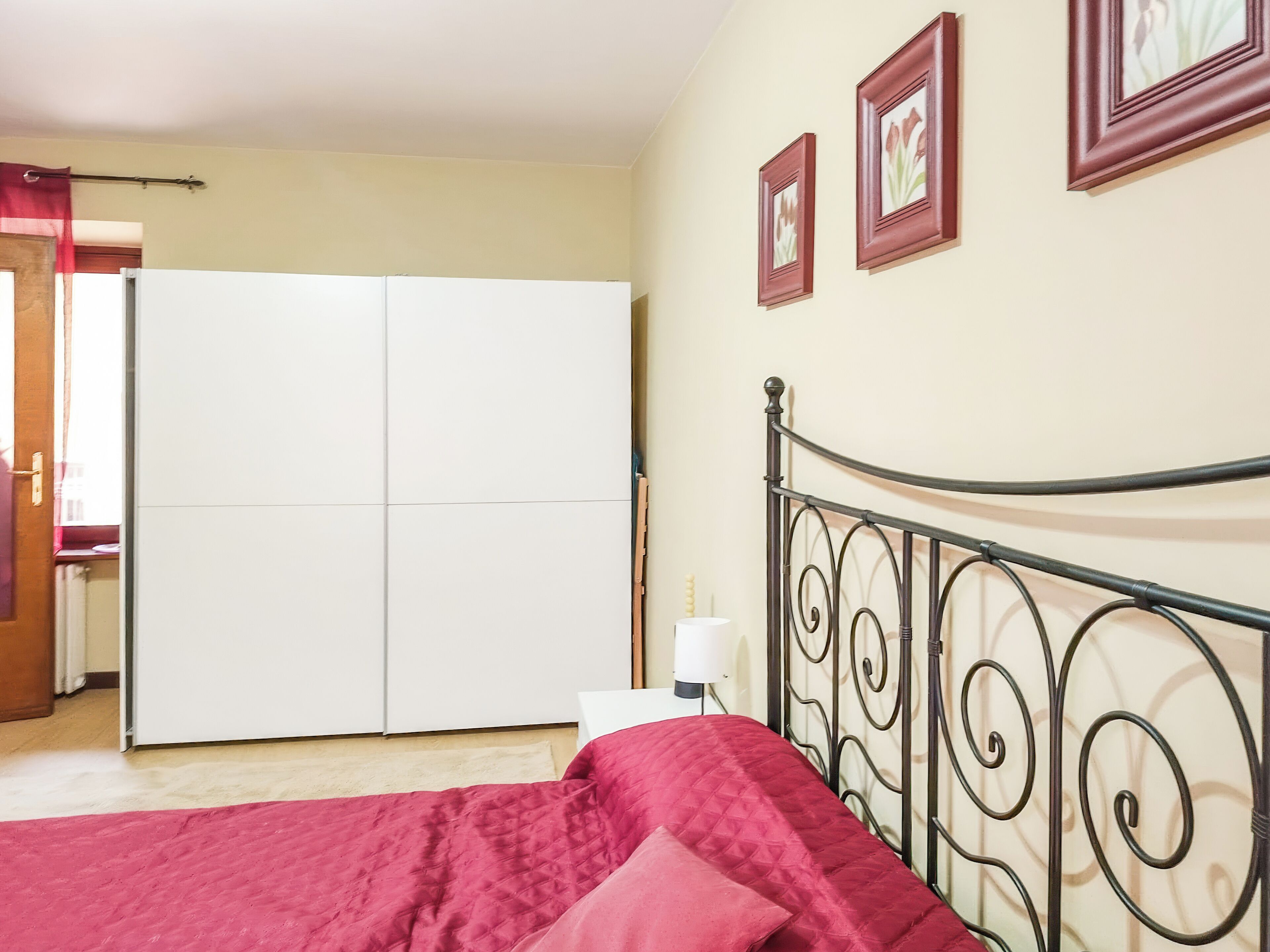 A bedroom with a bed, a wardrobe, and three framed pictures on the wall.