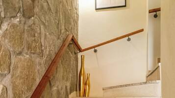Una escalera con pared de piedra, barandilla de madera y un cuadro enmarcado en la pared.