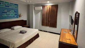 Habitación de hotel con cama, mesita de noche de madera, espejo y aire acondicionado instalado en la pared.