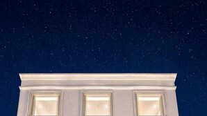 Ein Hotel mit moderner Fassade, zahlreichen beleuchteten Fenstern und einem Empfangsbereich, der einen Einblick in den Innenraum bietet.