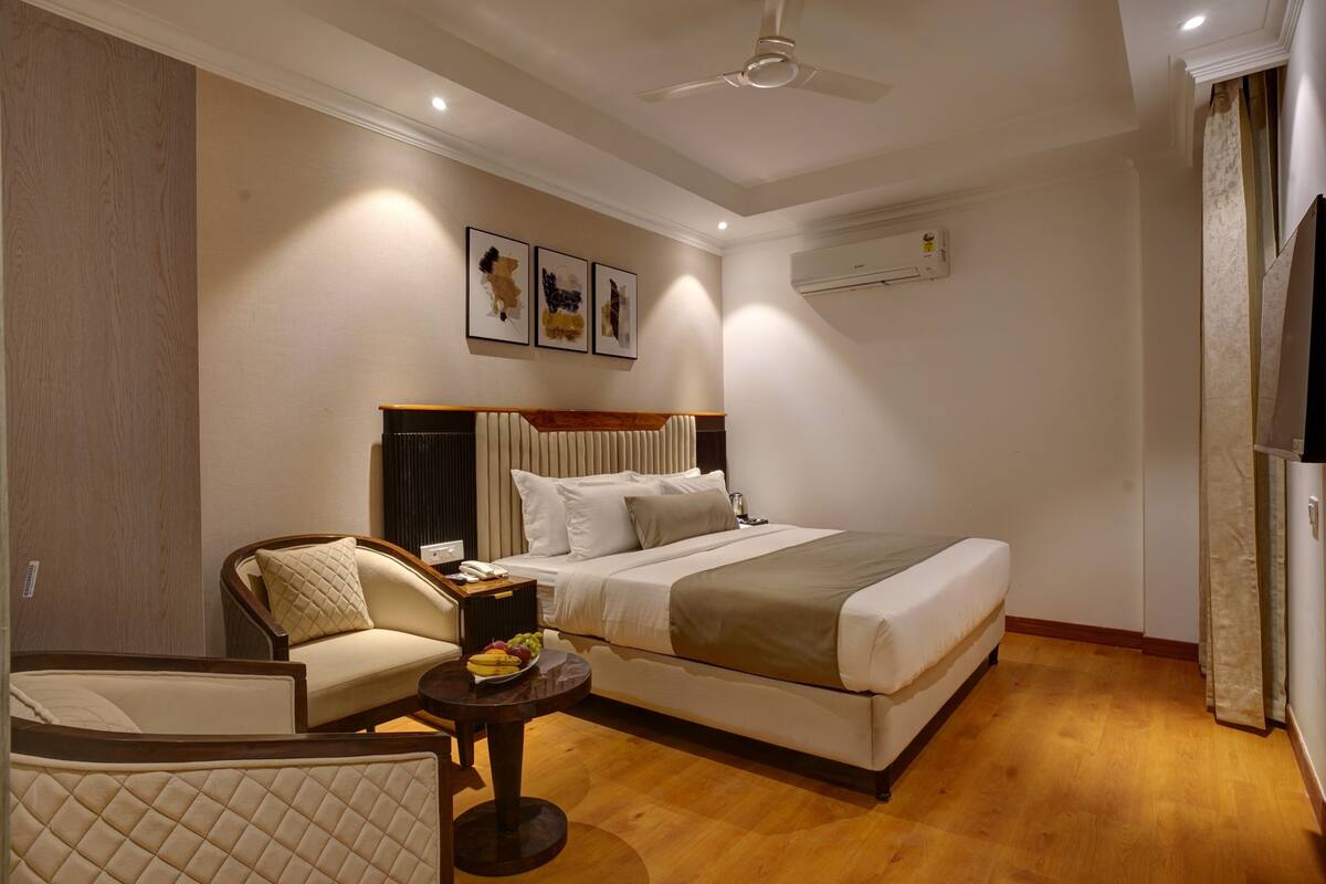 Una habitación de hotel con cama, una silla, una mesita con fruta y obras de arte en la pared.