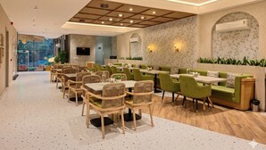 Ein modernes Restaurant mit einer langen Theke, grünen Sitzmöbeln und einer Wand mit Muster.