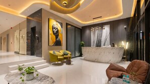 Eine moderne Lobby mit Empfangsbereich, Sitzgelegenheiten und einem großen Kunstwerk an der Wand.