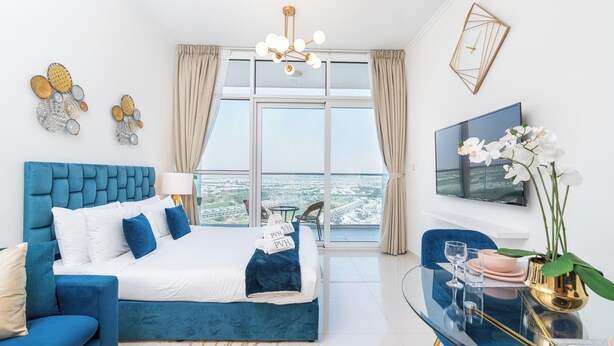 Een moderne hotelkamer met een groot bed, een zithoek met een glazen tafeltje en uitzicht op de stad.