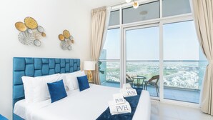 Een hotelkamer met een groot bed, uitzicht op de stad en een balkon met een tafel en stoelen.