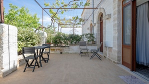 Eine Terrasse im Freien mit Tisch und Stühlen, einer Pergola und einer Steinmauer.