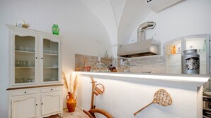 Eine Küche mit weißen Schränken, einem an der Wand angelehnten Holzlöffel und einem modernen Herd.