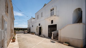 A narrow street with white buildings, a gated entrance, and potted plants. - Lamapecora - Salone Apartment with Balcony, Wi-Fi and Air Conditioning (Fasano)