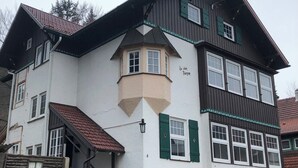 Un edificio de varios pisos con una torre en esquina, ventanas amplias y una base de ladrillo.