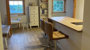 Cocina compacta con barra, suelo de madera y un armario blanco.