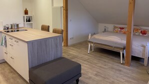 Un dormitorio moderno con techo inclinado, una cama con almohadillas florales, una mesita de noche y una lámpara de noche pequeña.