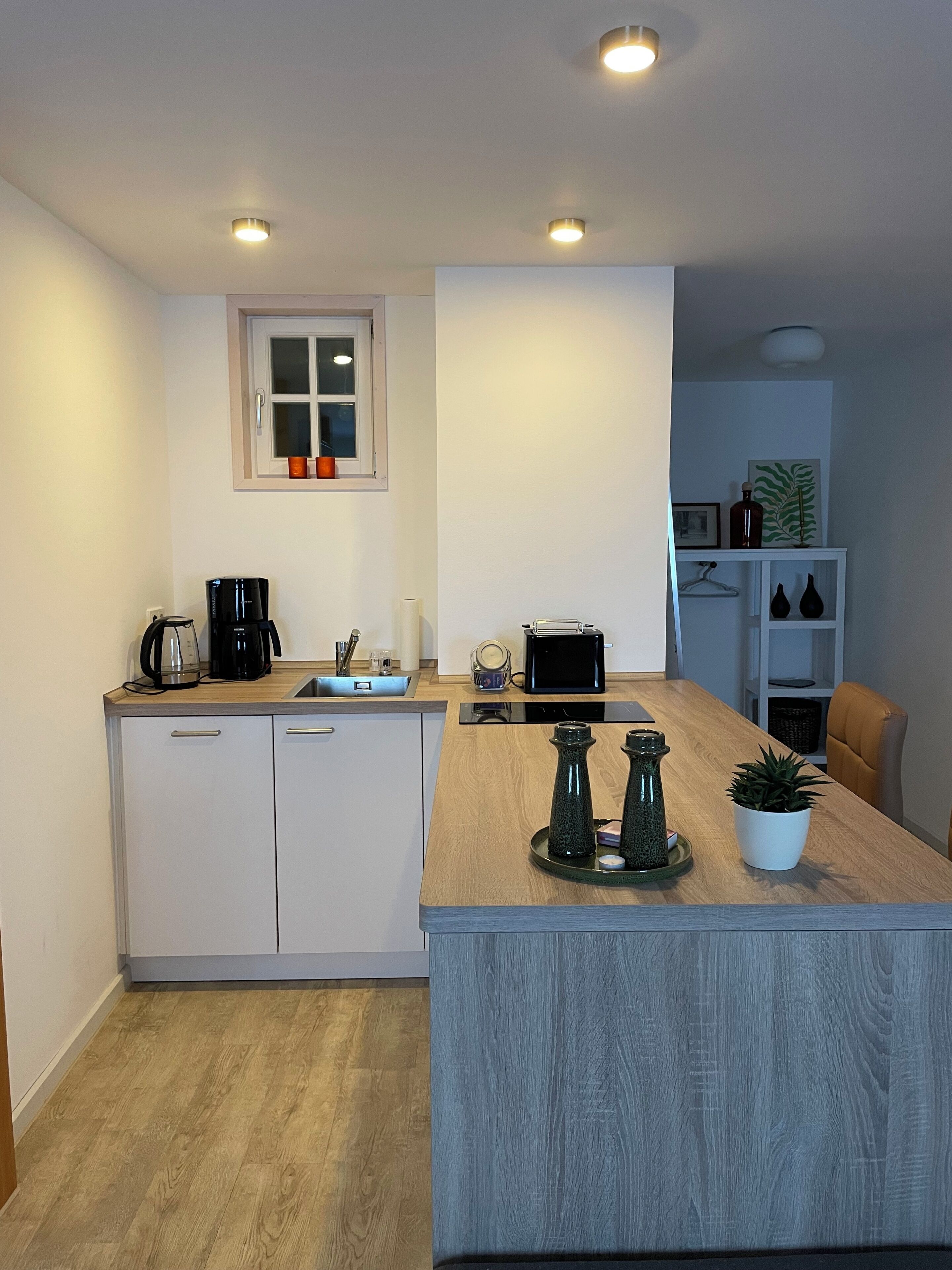 A modern kitchen with a wooden countertop, built-in appliances, and a small island with decorative items.