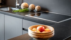 Een aanrecht met een schaal appels en drie bolvormige objecten.